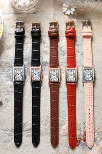 Five vintage quartz watches with rectangular dials and textured leather straps on silk