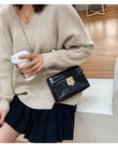 Detailed view of crocodile pattern crossbody bag with gold chain strap on beige sweater