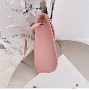Close-up of the side width and metal eyelet details on a pink faux leather mini crossbody bag