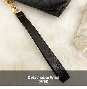 Detail of black quilted leather camera bag with golden lobster clasp and detachable wrist strap