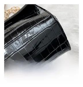 Close-up of black crocodile embossed leather texture with elegant gold chain strap