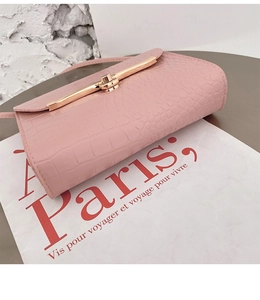 Detail of pink croc-embossed leather mini bag featuring a gold metal buckle closure