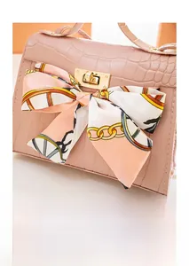 Detailed macro shot of pink crocodile texture handbag with silk scarf bow and gold lock