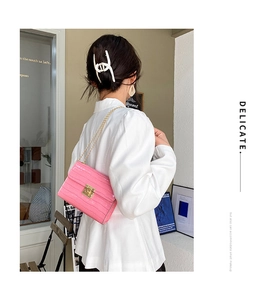 Pink crocodile pattern crossbody bag with golden chain strap shown on model shoulder
