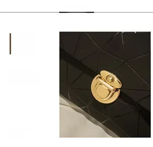 Detail of elegant gold metal lock clasp on black geometric textured crossbody bag