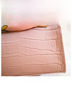 Detail of pink crocodile embossed PU leather texture on a mini kelly style handbag