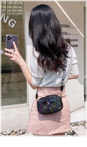 Outdoor street view of a black crossbody camera bag with colorful geometric patterns