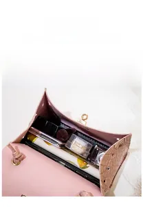 Internal capacity of pink croc-embossed mini bag holding smartphone and cosmetics