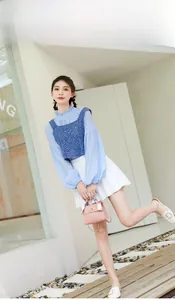 Fashion model in light blue blouse and navy vest carrying a pink Kelly bag with silk scarf