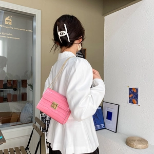 Pink faux crocodile leather crossbody bag with gold chain strap in a lifestyle street view