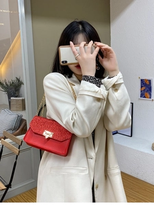 Sac à rabat à paillettes rouges avec chaîne dorée porté sur un blazer blanc chic