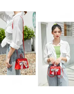 Detail of red crocodile texture handbag featuring floral silk scarf and metal buckle