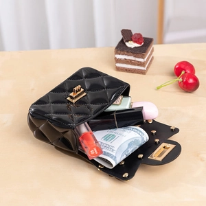 Quilted black jelly bag with gold lock and chain shown with lipstick and cash accessories
