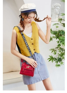 Detail of red patent leather crossbody bag with lettered wide strap and gold clasp