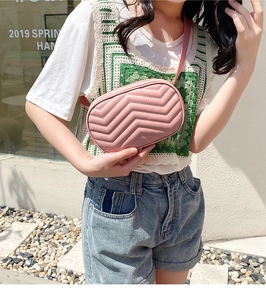 Détail d'un sac bandoulière matelassé rose avec motif à chevrons sur un mannequin