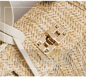 Detail of V-shaped straw weave handbag with golden twist lock and leather strap