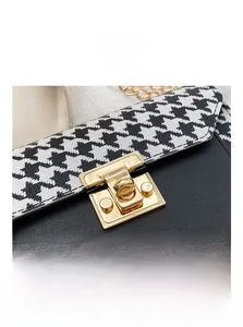 Close-up of golden metal lock and houndstooth pattern on a chic crossbody chain bag