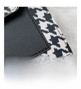 Detail of neat stitching on houndstooth fabric and black lychee grain leather handbag