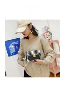 Close-up of houndstooth crossbody bag with gold buckle and chain on a model