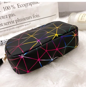 Close-up of black crossbody camera bag with colorful geometric patterns and gold zipper