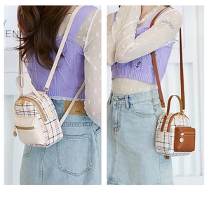 Detail of mini plaid backpack showing contrasting faux leather panels and zipper front pocket