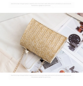 Detail of hand-woven straw crossbody bag featuring white faux leather trim and gold chain