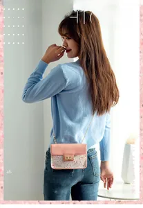 Detail view of pink sequin crossbody bag with gold chain strap worn on person