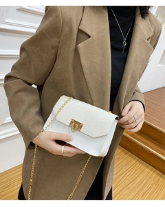Détail d'un mini sac carré blanc pailleté avec un fermoir métallique doré en forme de cœur