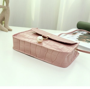 Macro detail of crocodile texture on pink faux leather bag with elegant pearl clasp