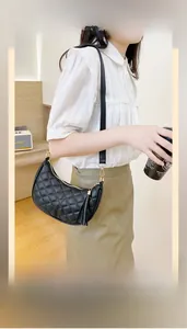 Close-up of black quilted crescent shoulder bag with golden hardware and leather tassel