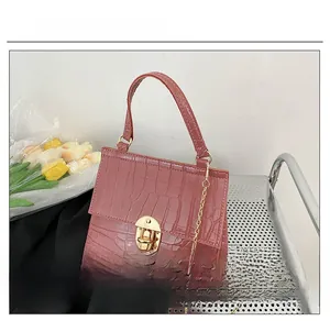 Close-up of pink crocodile pattern leather mini handbag with gold metal twist lock