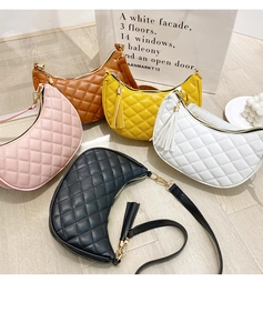 Detail view of five quilted hobo bags in various colors on a wood floor with tassels
