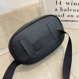 Sac banane ovale noir classique avec sangle réglable sur un fond en bois clair