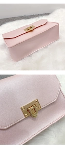 Dettaglio macro della borsa in pelle perlata rosa con trama fine e fibbia a U in metallo oro