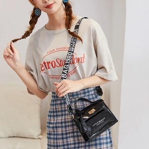 Black patent leather mini Kelly crossbody bag with white typography and wide shoulder strap