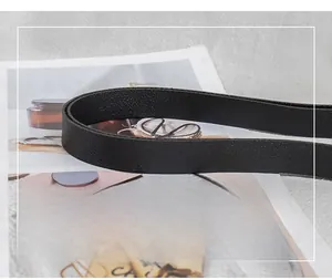Close-up of black litchi pattern leather shoulder strap on lifestyle magazine background