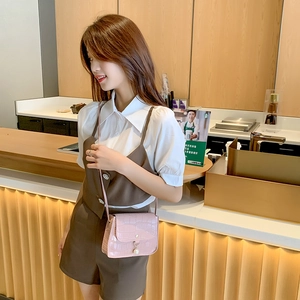 Pink crocodile pattern mini crossbody bag with pearl pendant shown on a model in a cafe