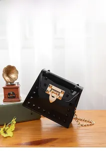 Close-up of black jelly bag with pyramid studs and golden chain on wooden table