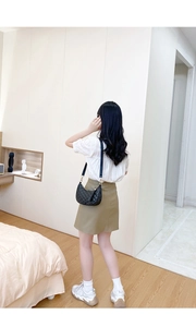 Back view of model wearing a black quilted crescent bag with a gold zipper detail