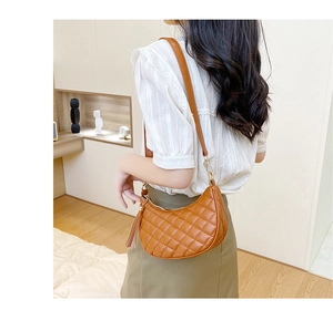 Détail de près d'un sac à bandoulière matelassé marron avec pompon en cuir élégant