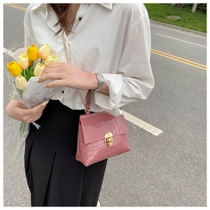 Detail of pink crocodile pattern mini bag with golden circular twist lock and chain strap