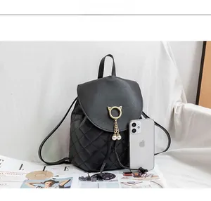 Detail of mini black quilted backpack with golden cat ear ring and pearl tassel decor