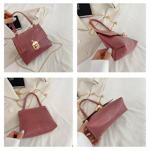 Detail view of pink crocodile-patterned mini bag with gold hardware and chain strap