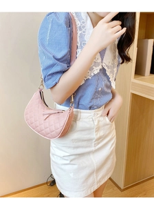 Close-up of pink quilted crescent shoulder bag with tassel detail worn by model