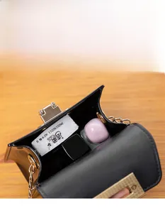 Detail showing the compact interior of a black mini jelly bag with lipstick and tissues