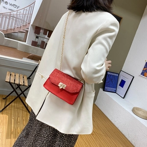 Petit sac bandoulière rouge à paillettes avec chaîne dorée et fermoir carré sur modèle