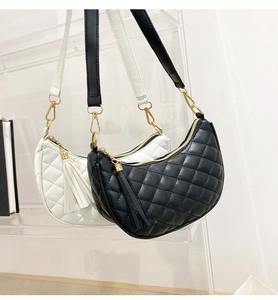 Close-up of quilted crescent shoulder bags with gold zippers and long tassel charms