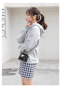 Street style shot of black patent leather jelly bag with gold studs and chain strap