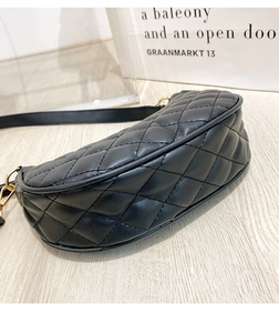 Close-up of black quilted leather texture and gold hardware on the elegant crescent bag