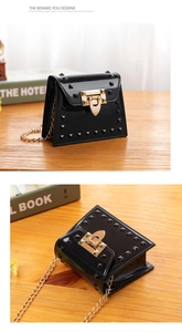 Detail of black patent leather jelly bag with studs and golden chain strap